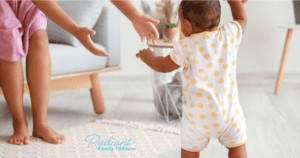 Parent watching toddler walk- developmental milestones